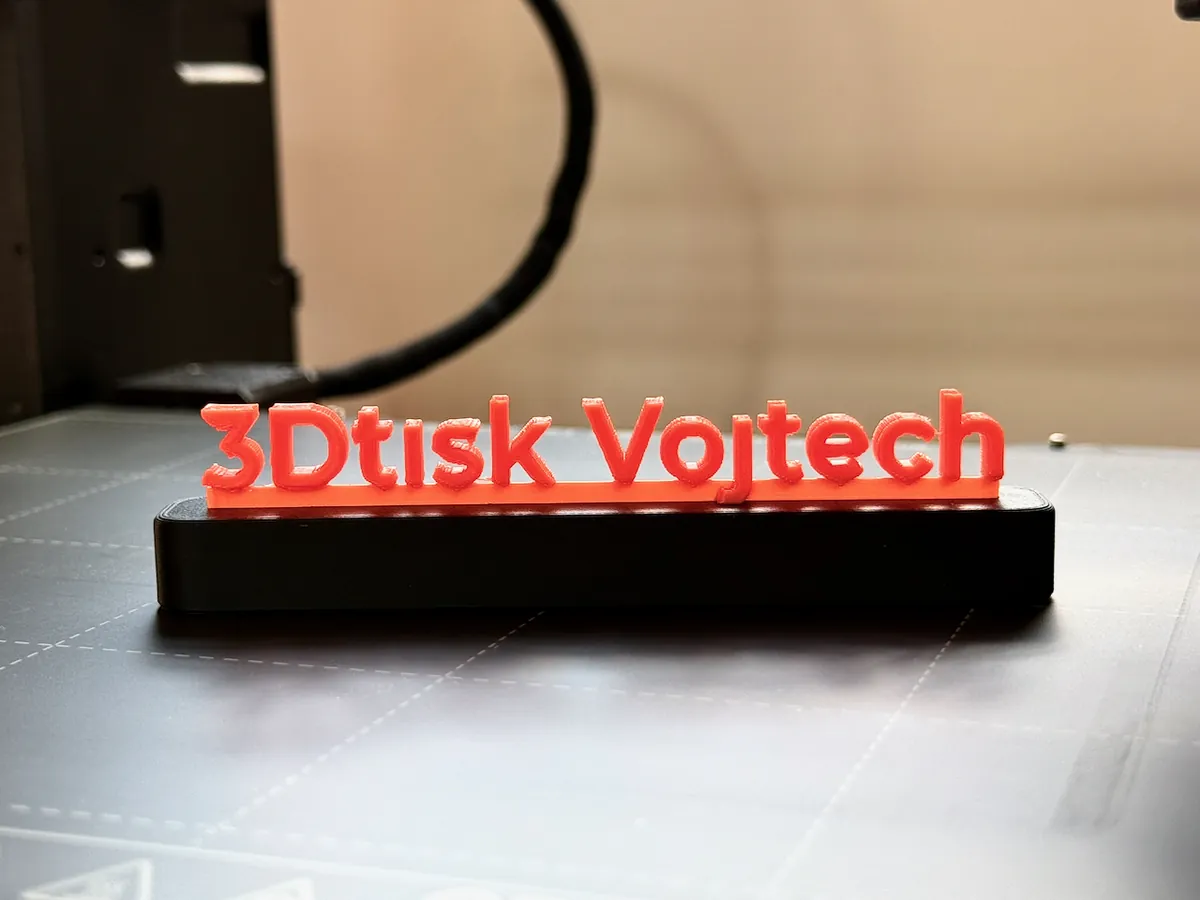 3D tištěný nápis 3Dtisk Vojtěch v oranžové na černém stojánku